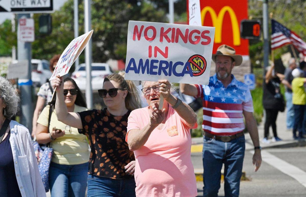 A group crosses Clovis Avenue as an estimated 400 or more of all ages gathered at the corner of Shaw and Clovis avenues for a Hands Off rally with the theme No Kings Saturday, April 19, 2025 in Clovis.