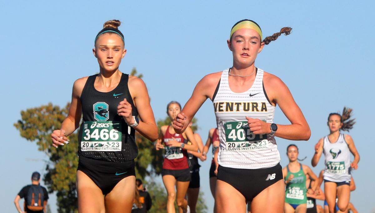 Santiago Corona junior Rylee Blade (second, 16:45.8) and Ventura High junior Sadie Engelhardt (first, 16:39.3) lead the pack during the Bill Buettner invitational flight of the 44th annual ASICS Clovis Invitational at Woodward Park on Oct. 7, 2023.