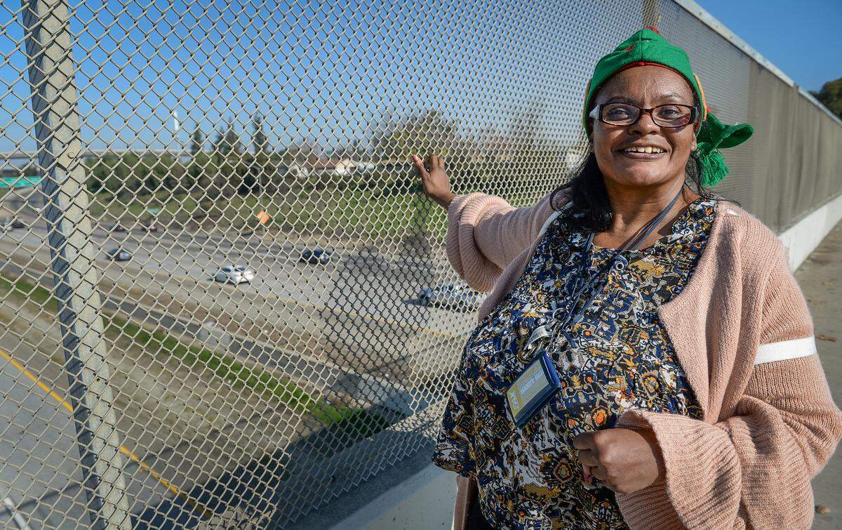 Cheryl “Monique” Turks, 47, of Fresno, smiles during one of hers sessions of waving to drivers on Highway 41 from the Belmont Avenue overpass on Wednesday, Jan. 2, 2019.
