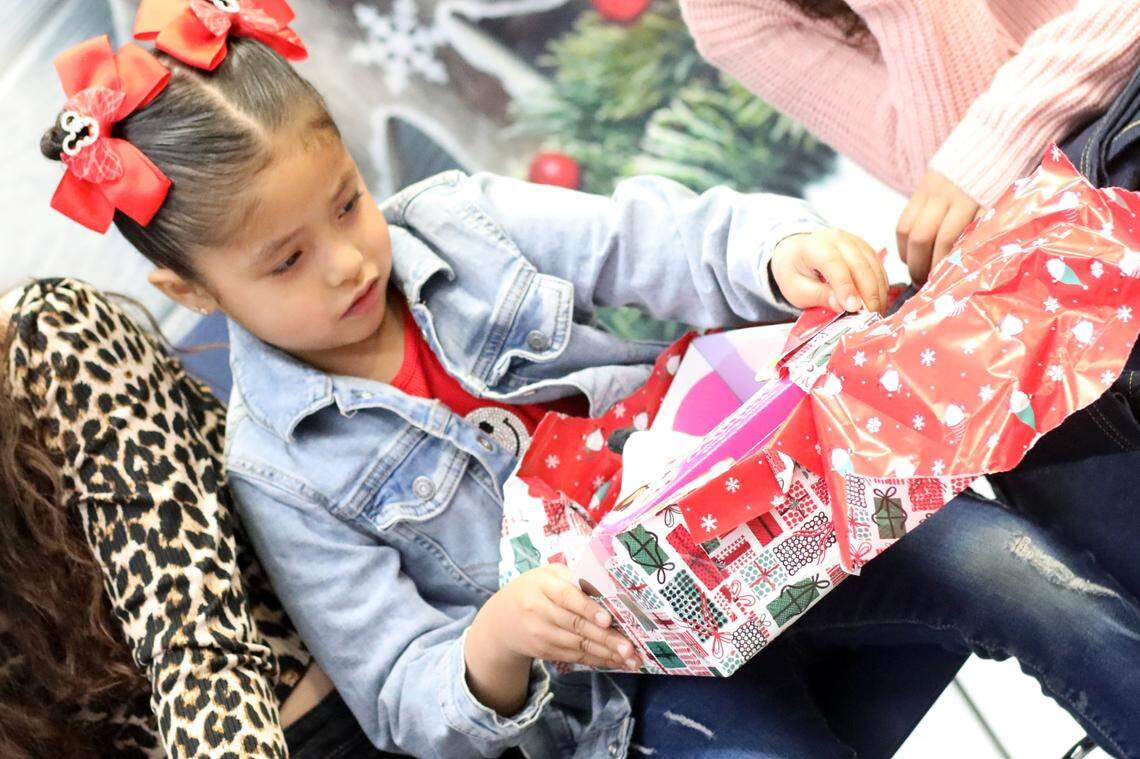 Damaris Ayala, de 5 años, abre un regalo de Santa Clos durante el evento de Navidad de la Familia Migrante 2023 que se llevó a cabo en la biblioteca de la Firebaugh High School el 13 de diciembre.