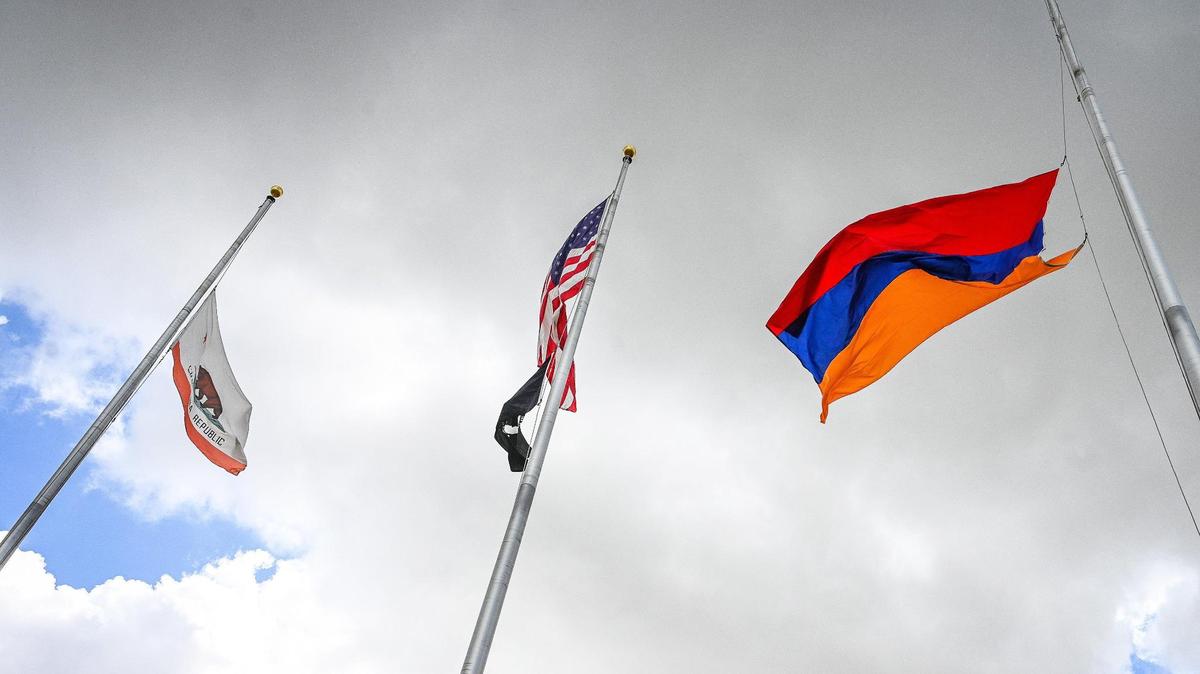 The Armenian flag, at right, joins the American Flag, center, and the California state flag on flagpoles in front of Fresno City Hall in an April 2022 commemoration of the Armenian genocide.