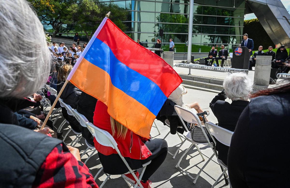 A woman holds an Armenian flag as Fowler City Councilmember Karnig Kazarian speaks during the annual Armenian Genocide Commemoration and flag raising ceremony at Fresno City Hall on Friday, April 22, 2022.