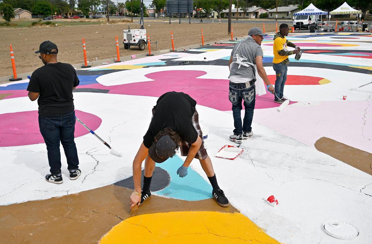 Volunteers and artists gathered to help paint a large street mural along Klette Avenue just north of California Ave. as part of the West Fresno California Avenue Neighborhood (CAN) initiative Saturday, May 6, 2023 in Fresno. Area residents and artists gatherd to paint the permanent mural as part of a revitalization effort.