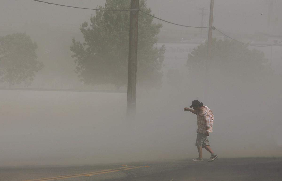 Duststorms like this one that blasted Fresno, Ca. in June, 2012, can carry millions of spores from the fungus that causes Valley Fever. A man tries to navigate through heavy winds and dust blowing along G Street in downtown Fresno.