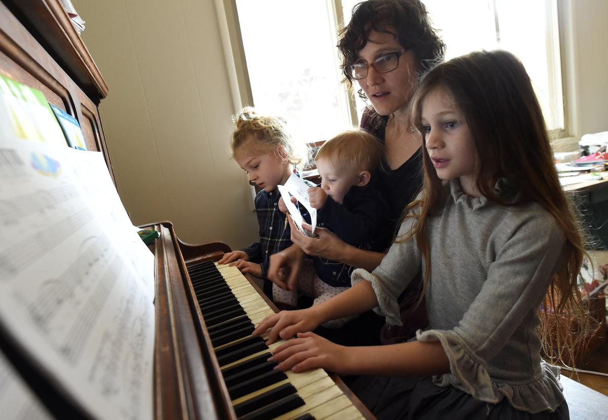 With 15-month-old Sylvia on her lap, stay-at-home mom Christa Pehl Evans watches 7-year-old Violet practice a Christmas carol, as Harvey, 5, explores the keys. Pehl Evans says she was berated by Fresno County Superior Court Judge James Petrucelli during jury duty selection after she asked to be excused to care for her children.