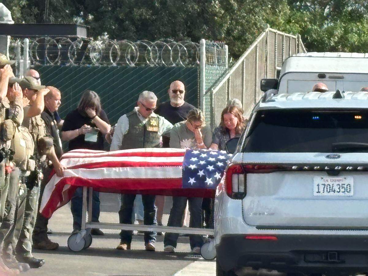 Sheriff Mike Boudreaux, center, glances down as the body of a slain Tulare County deputy arrives to the Tulare County Coroner’s Office in Tulare, California on Thursday, April 9, 2026.