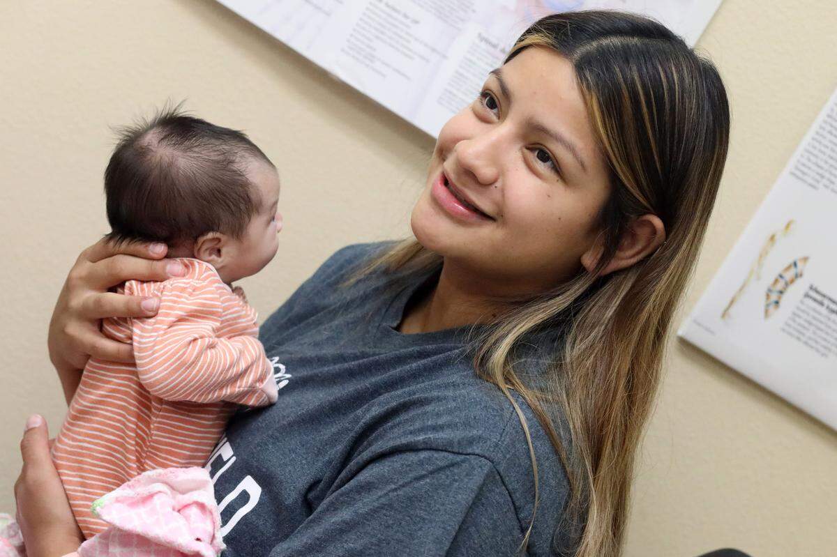 Sofia Lira escucha las instrucciones del doctor pediatra Rodrigo De la Cruz durante una revisión que le hizo a la bebé en la clínica Altura Centers for Healths en el oeste de Tulare el 7 de septiembre del 2023./Sofia Lira listens to pediatrician Dr. Rodrigo De la Cruz’s instructions during a checkup on the baby at the Altura Centers for Healths clinic in west Tulare on Sept. 7, 2023.