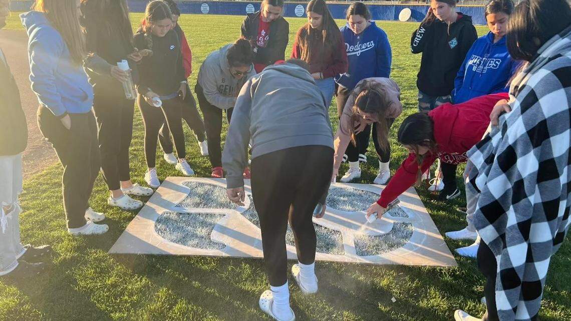 Hanford West softball players paint on the No. 2 in memory of Marissa Cardona who was killed in a car crash on Saturday, March 5, 2022.