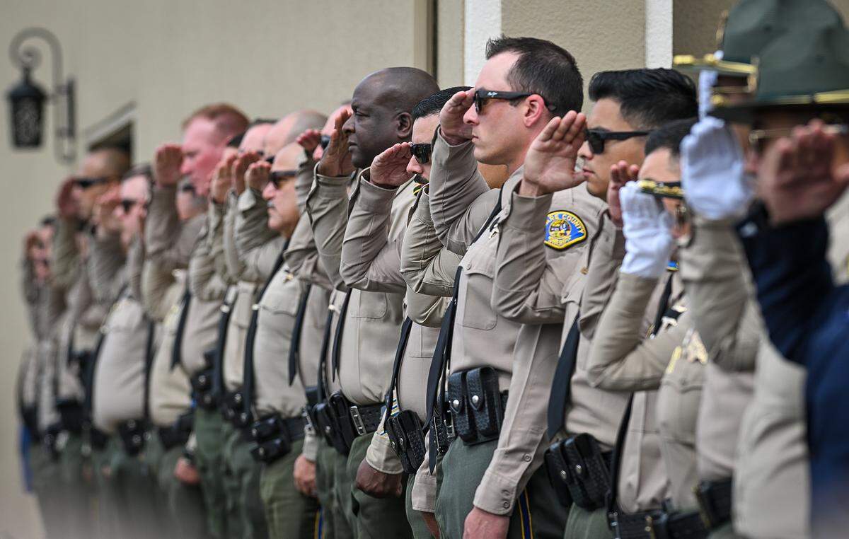 Tulare County Sheriff’s deputies salute as the body of Fallen TCSO Deputy Randy Hoppert is carried into Salsar and Dillard Funeral Home in Visalia on Monday, April 13, 2026. 