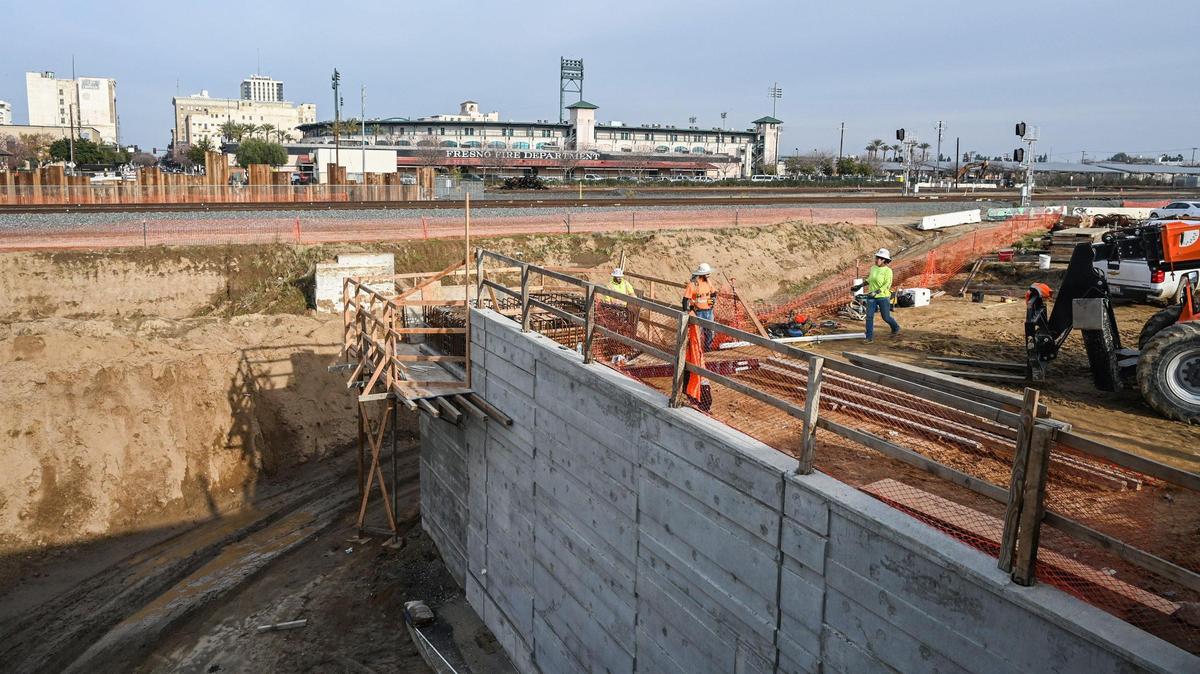 La construcción del Tren de Alta Velocidad de California continúa en el paso subterráneo de Tulare Street en el Chinatown de Fresno, el jueves 8 de diciembre de 2022. El muralista Mauro Carrera trabaja en un proyecto cercano con Fresno Arts Council y la Autoridad del Tren de Alta Velocidad de California.