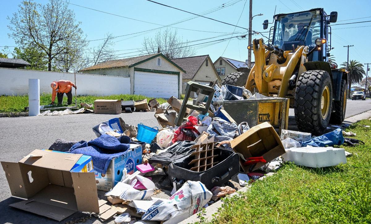 A city worker uses “the Claw” frontloader to scoop up residential trash left out on a street in southeast Fresno during Operation Cleanup in Fresno on Monday, April 8, 2024.