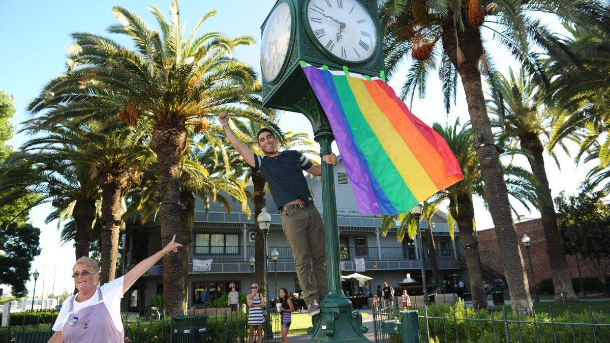 Jack Semirdzhyan, 23, of Merced, cheers after taping a rainbow flag to the clock at Bob Hart Square in 2013. The city of Merced on Monday, May 3, 2021 unanimously decided to fly the Pride Progress Flag will fly in Bob Hart Square  during June, which is national Pride Month.