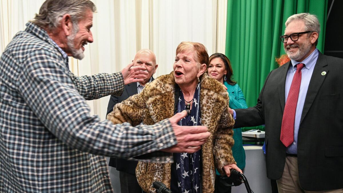 Sally Caglia, center, gets a hug from her brother Vince Caglia, left, as Fresno Chamber of Commerce CEO Scott Miller, right, watches after announcing Sally as the 2023 Leon S. Peters Award recipient in front of family and friends at CMAC in Fresno on Tuesday, Jan. 17, 2023.