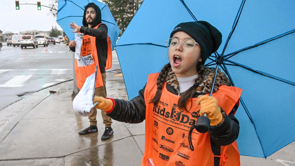 Penny Duarte, 10, sells Kids Day newspapers with her father Pete Duarte at the corner of Friant and Audubon in Fresno on Tuesday, March 12, 2024.