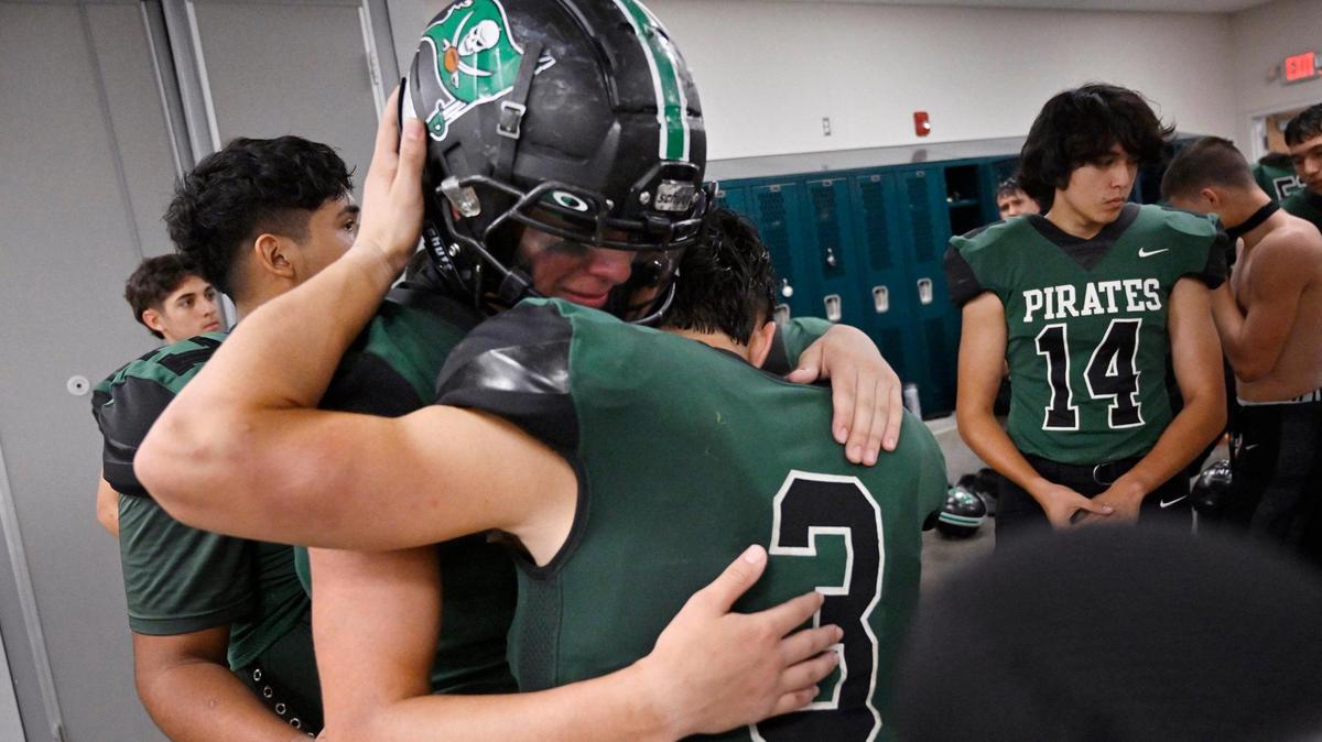 El corredor de Reedley Demetrius Vargas, a la derecha, abraza llorando a Malachi Ríos, a la izquierda, en el vestidor después del partido contra Roosevelt, la noche del viernes 25 de agosto de 2023, en Reedley.