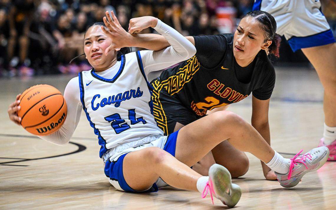 Clovis' Sadie Sin, let, falls to the floor while defended by Clovis West's Malohni Warren during their Central Section Division 1 girls basketball championship game at Selland Arena on Saturday, Feb. 28, 2026. 
