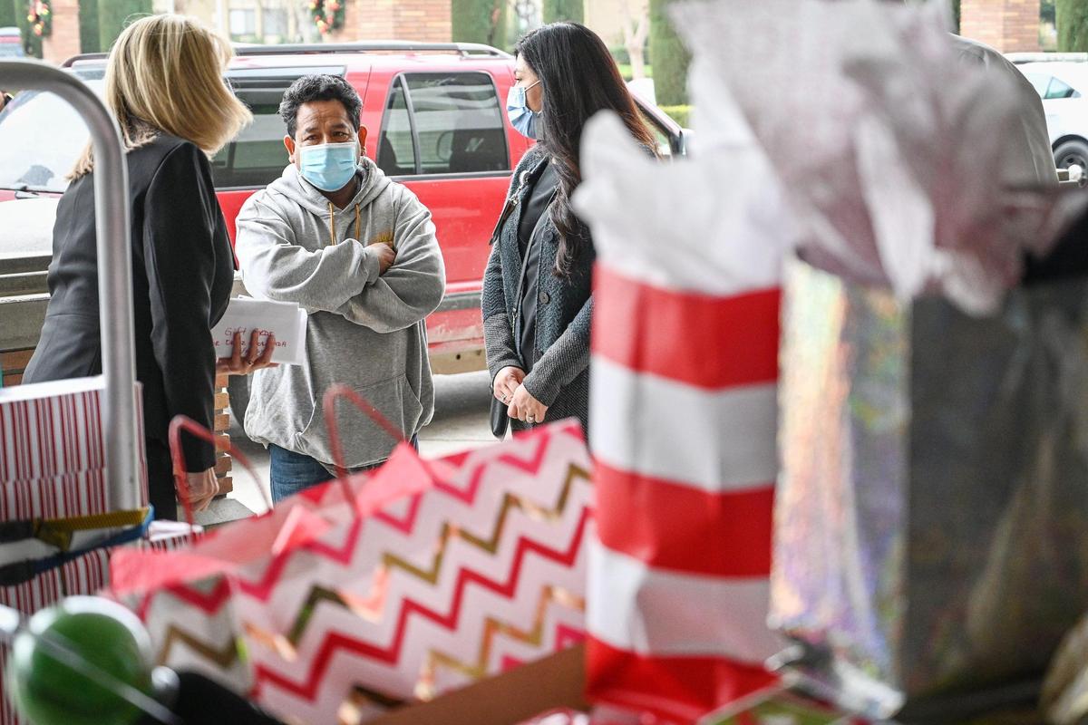 Sarah Putman, left, director of women & newborn health at Community Regional Medical Center, and CRMC social worker Stacy Gomez speak with Adrian Ortiz-Escobar after carts of donated toys and gifts were brought out for him and his family outside CRMC on Wednesday, Dec. 22, 2021.