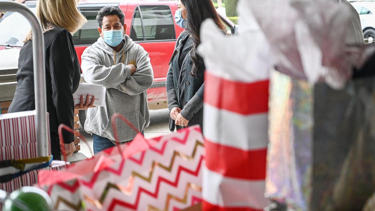 Sarah Putman, left, director of women & newborn health at Community Regional Medical Center, and CRMC social worker Stacy Gomez speak with Adrian Ortiz-Escobar after carts of donated toys and gifts were brought out for him and his family outside CRMC on Wednesday, Dec. 22, 2021.