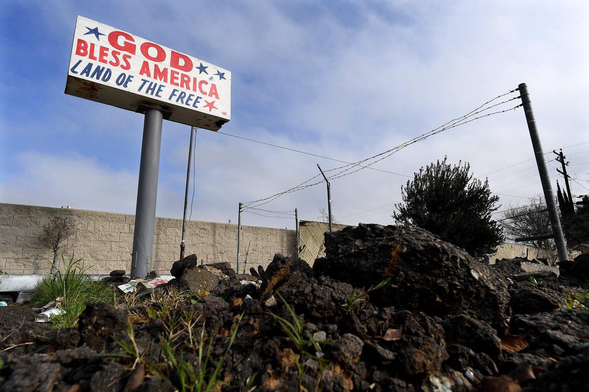 A sign of optimism stands over chunks of piled asphalt, on a previously commercially-used Elm Avenue parcel, in a southwest Fresno, Feb. 5, 2021. The area is dotted with brownfields- EPA designated land, previously used, where the presence of contaminates is known, which hinders future development without costly abatement.