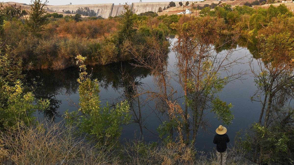 A man fishes the San Joaquin River with Millerton Lake’s Friant Dam seen in the distance Monday, Sept. 28, 2020 near Friant.