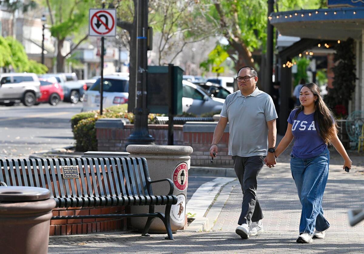 A couple strolls along Pollasky Ave. Wednesday, March 26, 2025 in Old Town Clovis. Cowboy Cleanup will bring one hundred volunteers together to clean the streets, shops and intersections of Old Town Clovis on Saturday, March 29 in preparation for rodeo events in April.