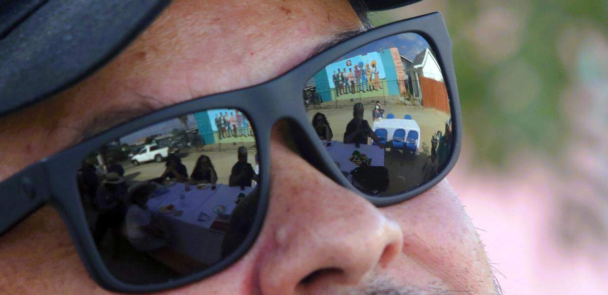 The resurrected 1968 mural drawn by Antonio Bernal is reflected on the sunglasses of the artist’s son, Hugo Hopping, at Oct. 22, 2023 memorial.