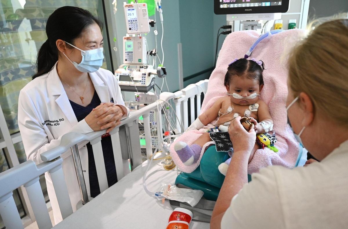 Dr. Wendy Wong, left, watches as Victoria Saypen, center, looks at a toy offered by nurse Wendy Medhurst, right, at Valley Children’s Hospital, Thursday, March 2, 2023 in Madera County.