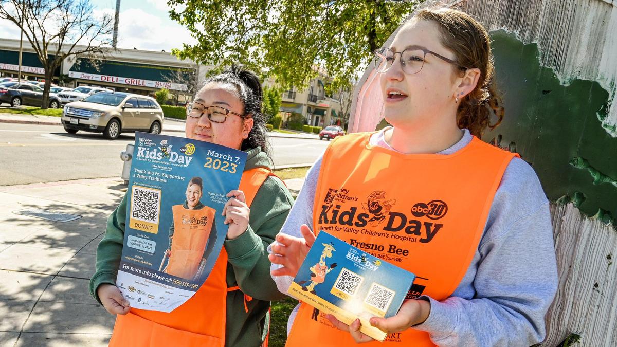 Fresno State pre-dental students Haylee McFall, right, and Rose Xiong pass out Kids Day postcards with QR codes to passing motorists to donate to the annual Kids Day benefit for Valley Children’s Hospital, near Fresno State on Tuesday, March 7, 2023.