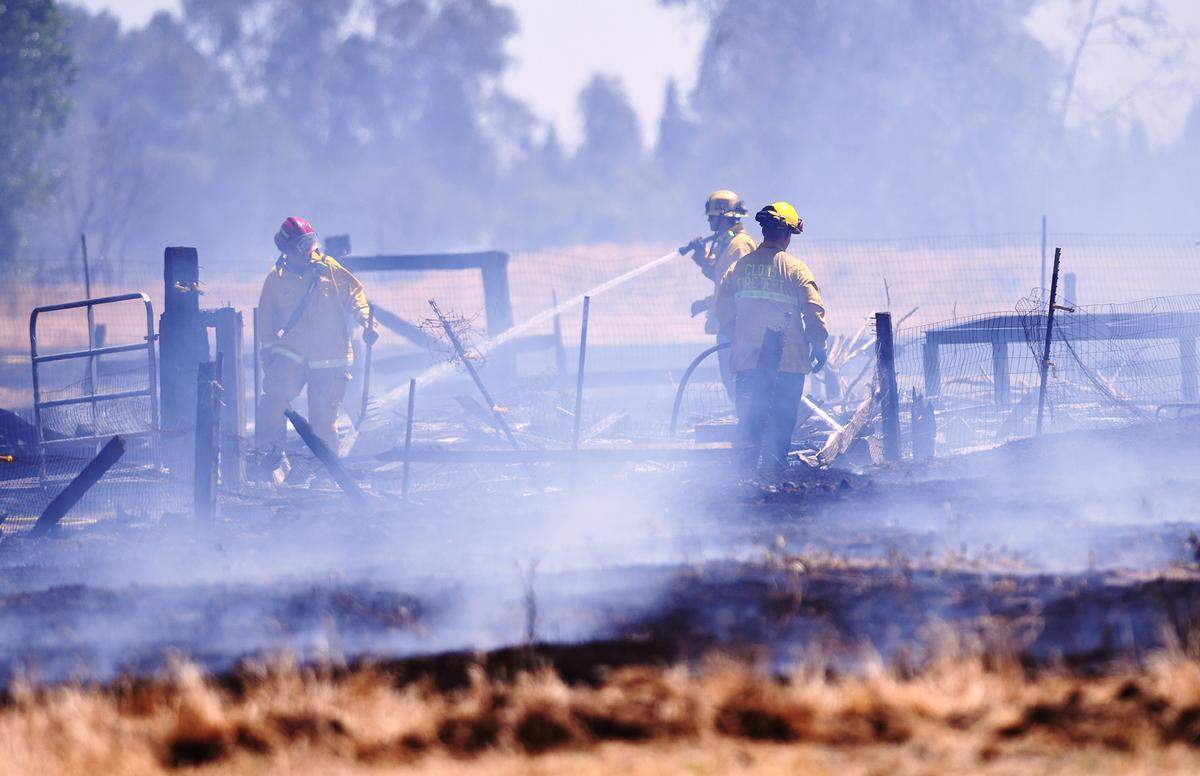 CalFire firefighters, along with Clovis Fire Department, extinguishe the last flames at the scene of a grass fire south of Teague Avenue and east of Fowler Avenue Friday afternoon, May 7, 2021 in Clovis.
