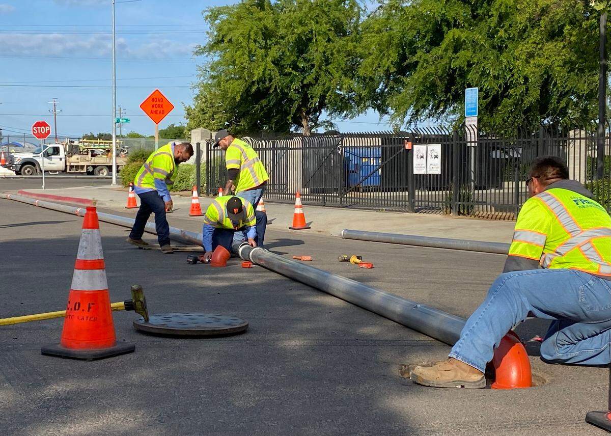 Public utilities crews from the city of Fresno work to install a 6-inch temporary pipeline on Saturday, May 6, 2023, at Brooks Avenue and Esther Way and to help move sewage after a 42-inch sewer line broke and created a sinkhole along nearby railroad tracks on Friday night. The broken pipe and sinkhole caused sewage to back up in the system in the central Fresno neighborhood.