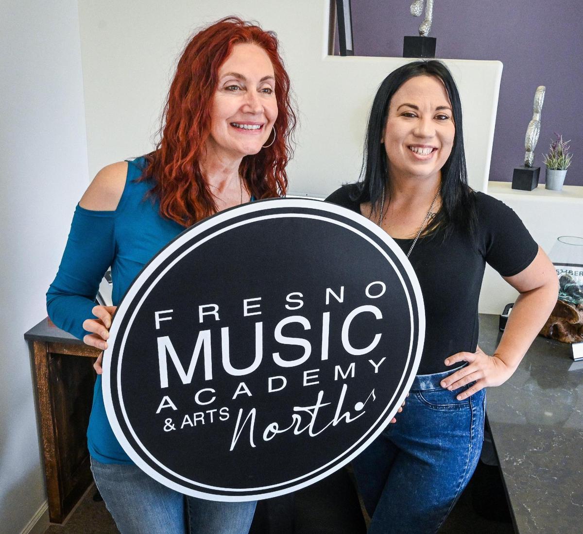 Debi Ruud, owner of Fresno Music Academy & Arts, holds up a new sign with office manager Allison Lanford the business’s new location in north Fresno on Tuesday, April 19, 2022.