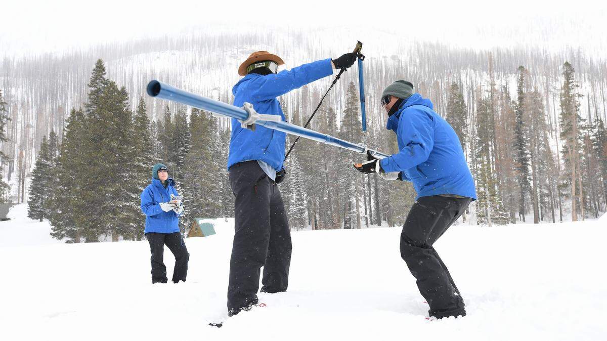 Workers with the California Department of Water Resources weigh a core sample taken from the snowpack at Phillips Station near Lake Tahoe to measure how much water is contained in the snow on April 3, 2023. A record snowpack this year has state and local officials bracing for the prospect of eventual flooding as the snow melts over the spring and summer.