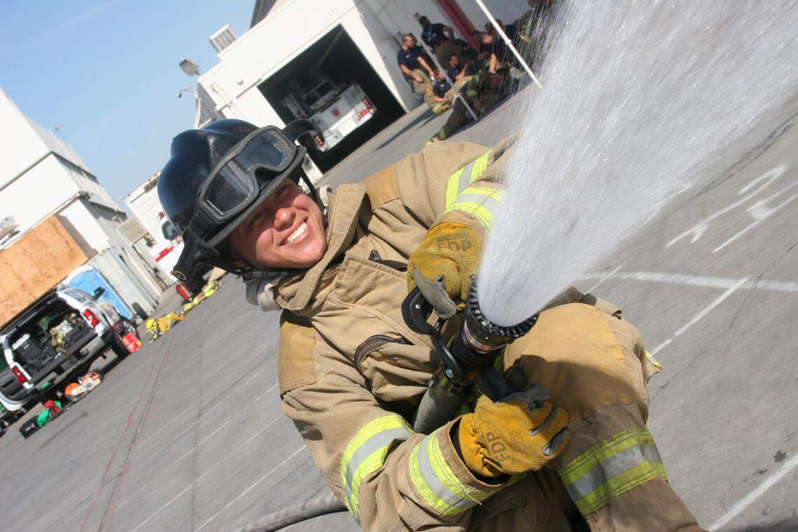 A participant in a firefighting training sprays a fire hose.
