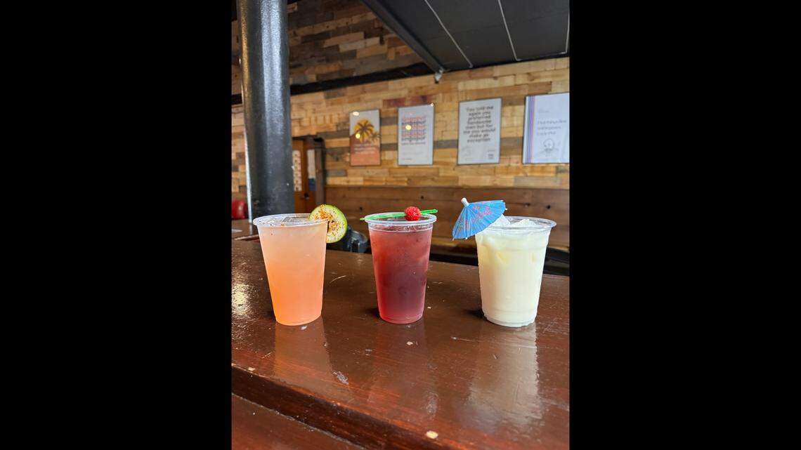 Three drinks from the sober bar at The Layover in downtown Fresno are, from left to right: the Watermelon Lime, with a lime wheel dusted with Tajín, the Shark Infested Berry drink, with a spear to fish for a shark, and the Horchatalada, made with creamy horchata, pineapple and coconut.