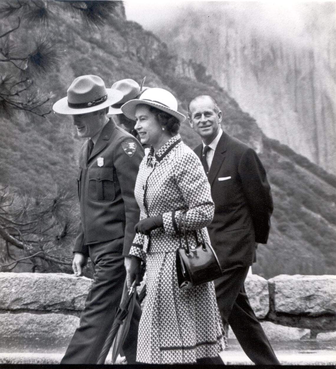 Queen Elizabeth II walks with rangers and her husband, Prince Philip, during her 1983 visit to Yosemite National Park with snow in the background.