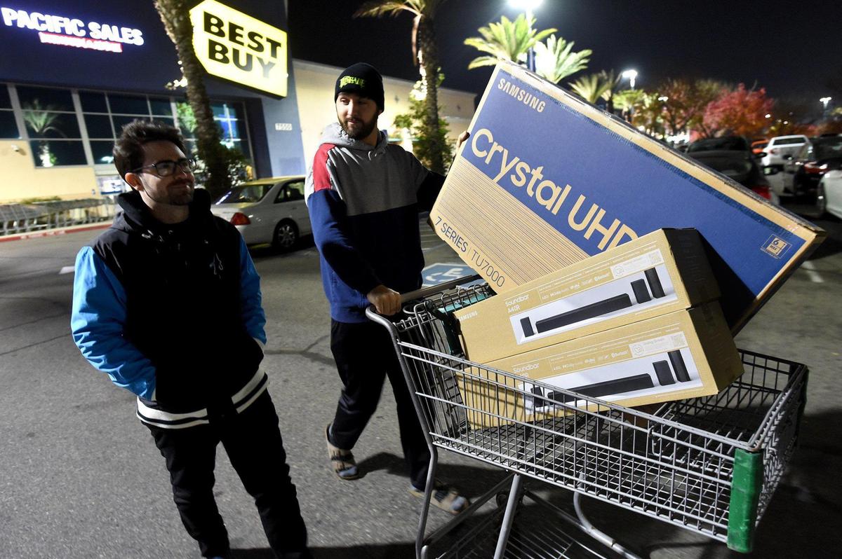 Black Friday shoppers Peter Vitale, left, and Sonny Singh, head to their car after scoring on a TV and sound bar at Best Buy at River Park shopping center at 4:30 a.m., at 5:30 a.m., Nov. 26, 2021.