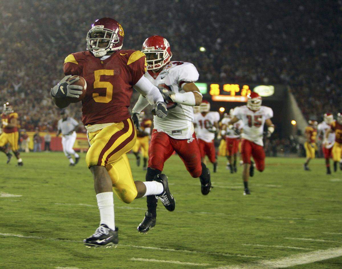 Reggie Bush #5 of the USC Trojans carries the ball past Matt Davis #26 of the Fresno State Bulldogs during the game at the Los Angeles Memorial Coliseum on November 19, 2005 in Los Angeles, California. The Trojans won 50-42.