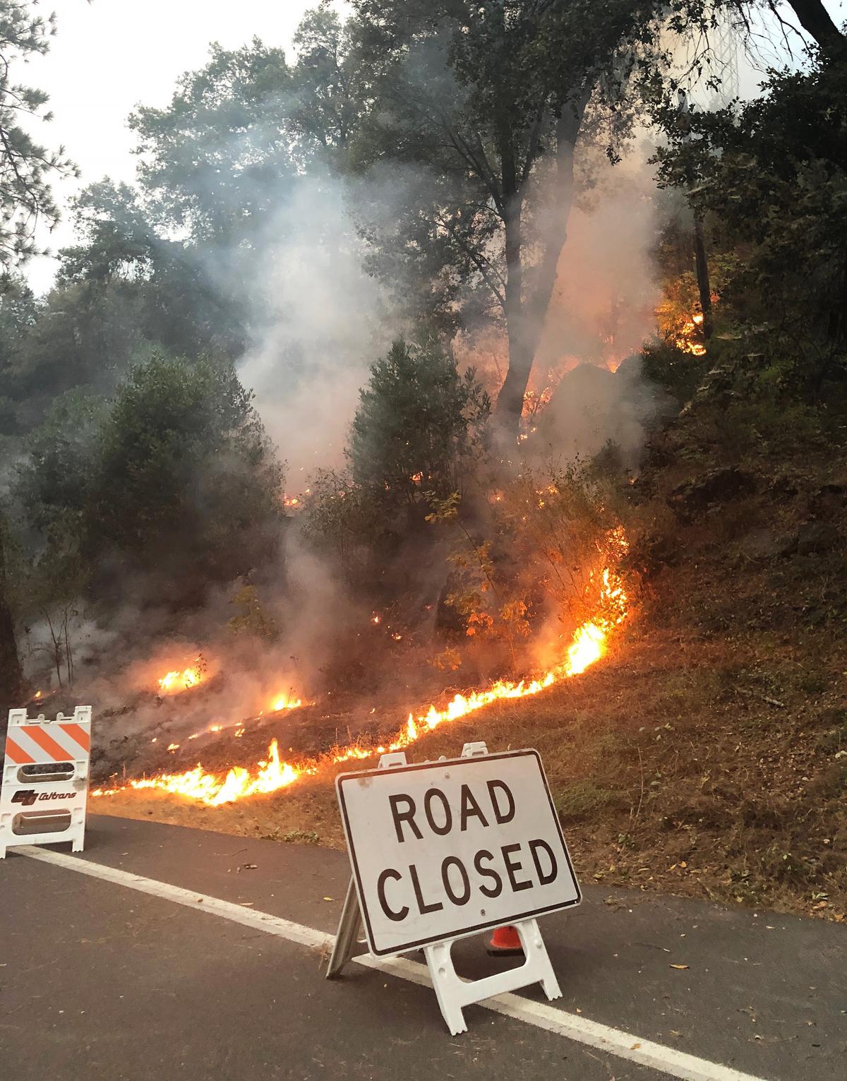 Fire burns at the side of the road near Arch Rock at the west gate entry to Yosemite National Park on Monday, Aug. 6, 2018. Yosemite National Park remains closed due to the Ferguson Fire but some residents of the private community of Wawona have been allowed to return to their homes. 