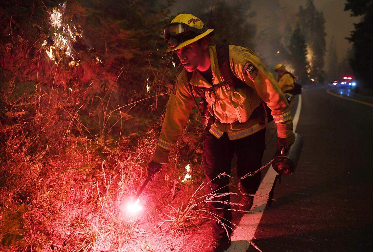 Cal Fire’s Ricardo Gomez sets fire to dry grass as part of a back-burning effort along Highway 168 at the edge of Shaver Lake in a bid to help slow the spread of the Creek Fire on Sunday, Sept. 6, 2020.