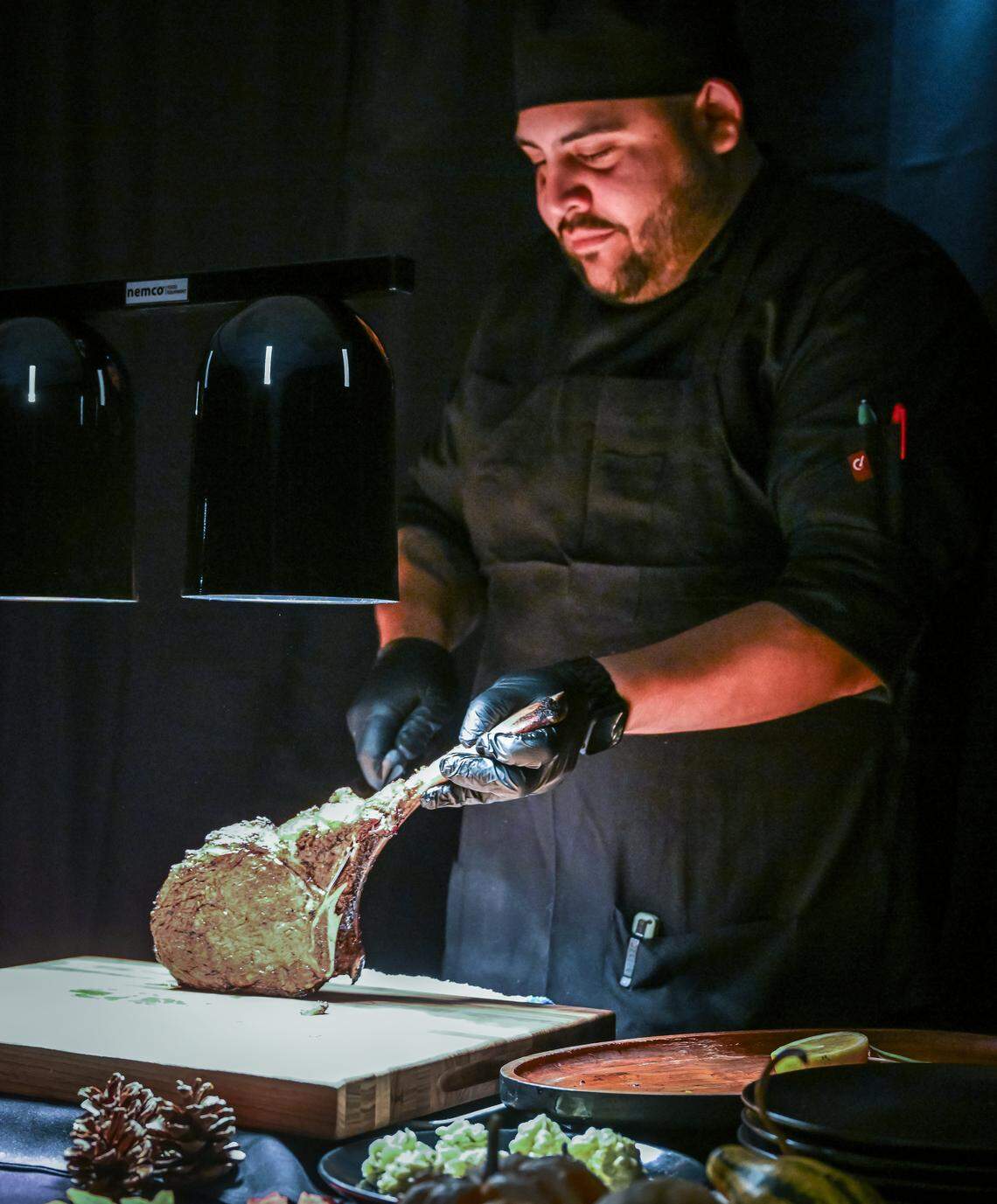 One of the chefs for The PM Lounge carves a tomahawk steak during a media event to promote the new Fresno members-only club.