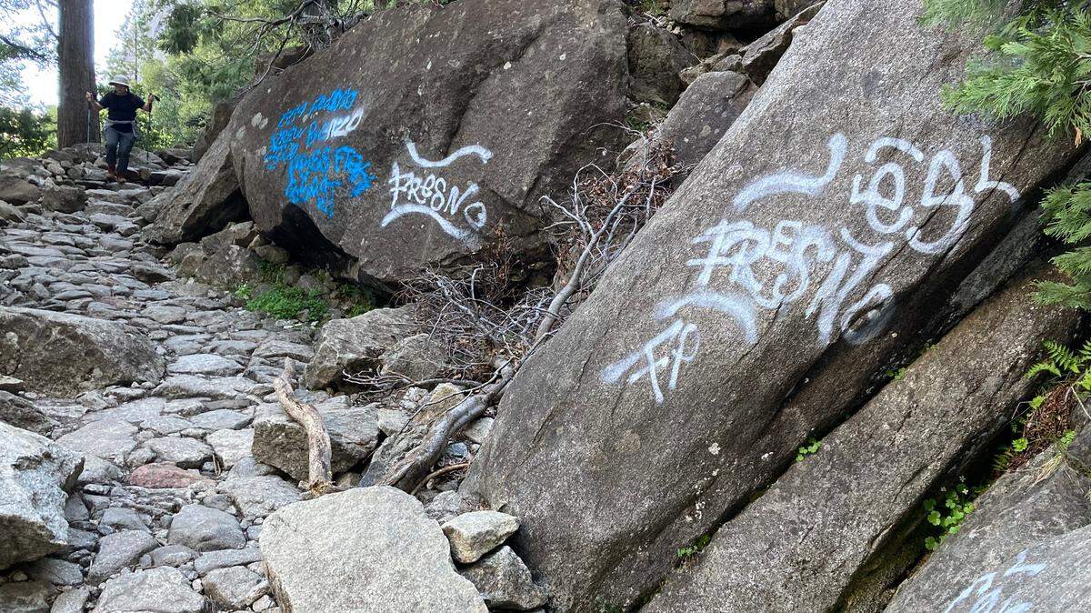 A hiker walks along the Yosemite Falls Trail in Yosemite National Park after vandals spray-painted graffiti on the rocks at about 30 different points along the trail. Park rangers are seeking the public’s help with photos, videos or other evidence in their investigation.