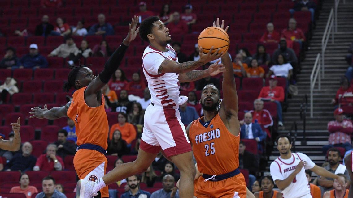 Fresno State guard Isaiah Hill drives to the rim by Fresno Pacific’s Michael Mensah, left, and Darrin Person, Jr., right, Monday, Nov. 7, 2022 in Fresno.