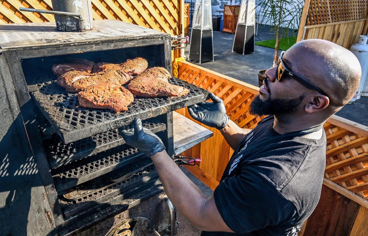James Woodard checks on tri-tip smoking on his vertical smoker at Smoking Woods BBQ food truck in Fresno’s Brewery District in downtown Fresno on Friday, Dec. 9, 2022.