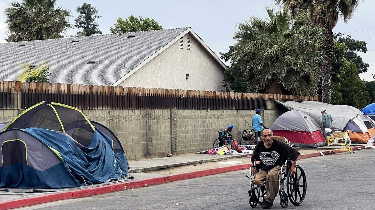 A man in a wheelchair is forced into the street due to people camping on the sidewalk at Poverello House in downtown Fresno.