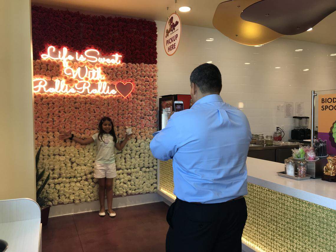 Angel Ponce of Fowler, takes his daughter Camila Ponce’s photo on her 10th birthday at the silk flower wall at Rollie Rollie Thai Rolled Ice Cream. Its new location is open at First Street and Nees Avenue.