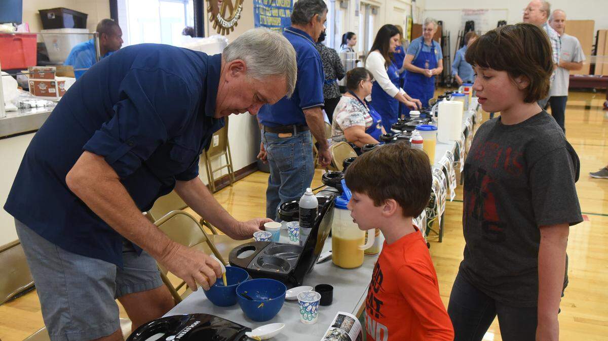 Breaking eggs to make an omelet under watchful eyes during Rotary club’s omelet and pancake breakfast.