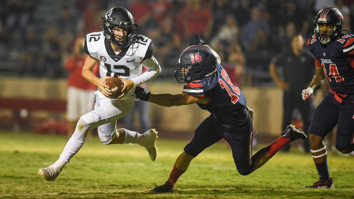 Hanford quarterback Cayden Muir rolls away from Memorial’s Jacob Rangel while looking for a target in the first half of their game at San Joaquin Memorial on Friday, Aug. 27, 2021.