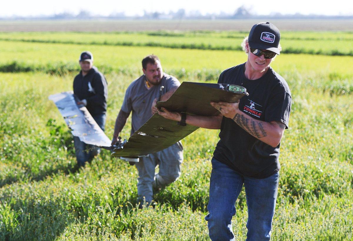 Josh Watson, right, helps carry the main propeller after pilot Mark Trinkle crashed his small crop-dusting helicopter after becoming entangled in power lines in a field Saturday, March 13, 2021 near Laton. Trinkle suffered only minor scrapes.