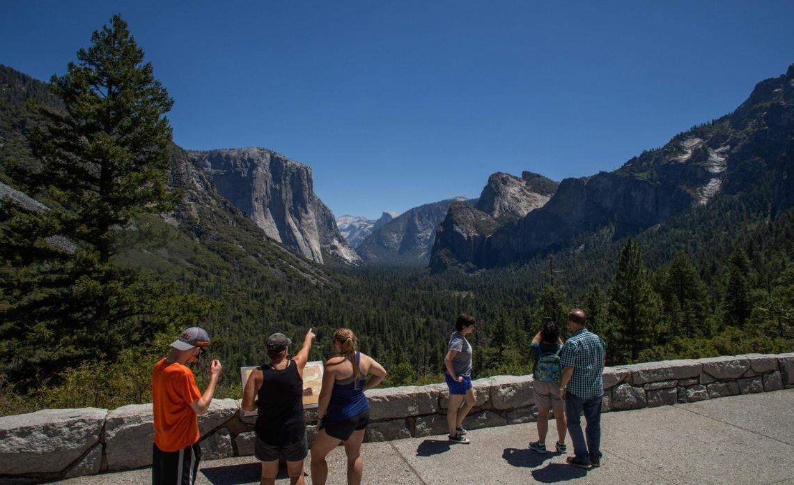 Visitors to the Tunnel View overlook in Yosemite National Park gaze upon nearby El Capitan and Half Dome in the distance.