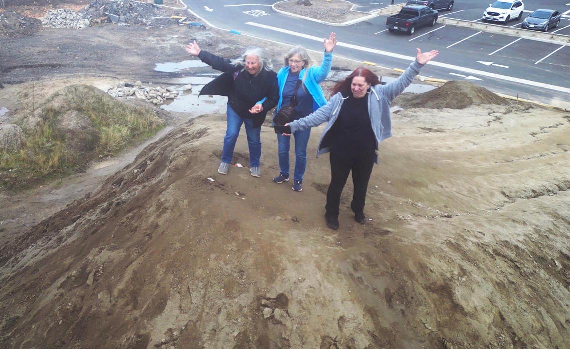 Lucy Matchel, left, Carol Eggink, center, and Elaine Hannah, right, pose for a photo on top of the mound of dirt dubbed Mt. Chipotle Friday, Jan. 3, 2025 in Oakhurst. Located next to a new Chipotle Mexican Grill, the mound may be permanently removed in a few days but until then the community of Oakhurst and others from around the Valley are enjoying the dirt made famous in social media posts.